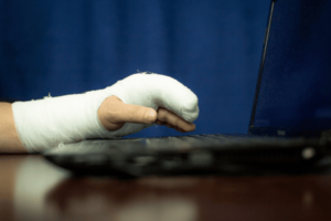 A man with a cast on his arm is working at a computer- incapacity planning