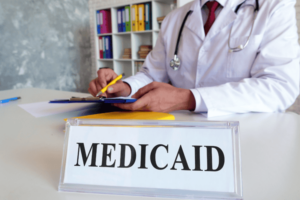 medicaid in missouri- plate with an inscription Medicaid and a doctor filling out documents