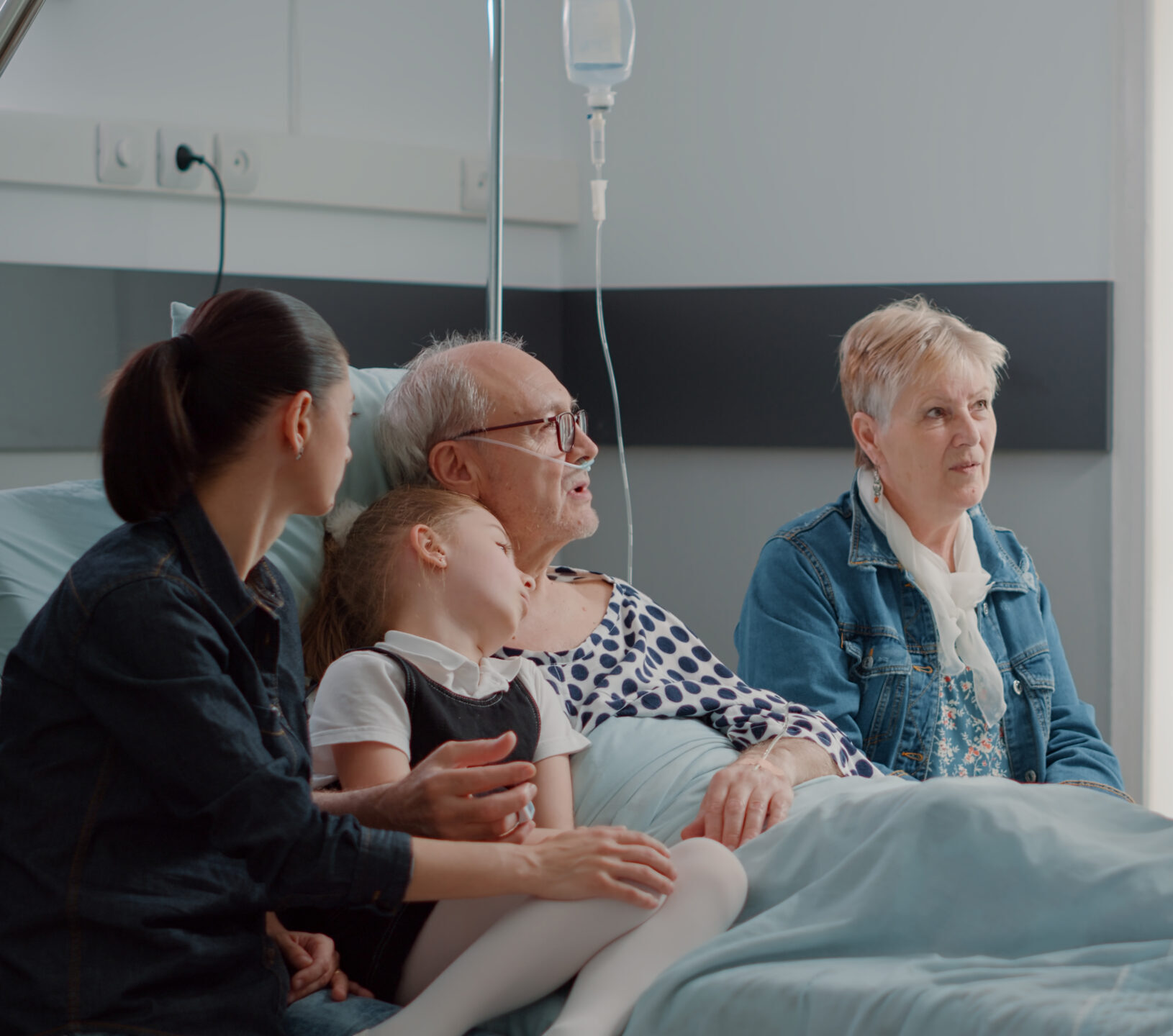 Older man in hospital with family.