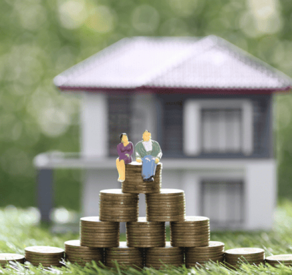 couple figurines on stack of coins with house in background- funding a trust concept