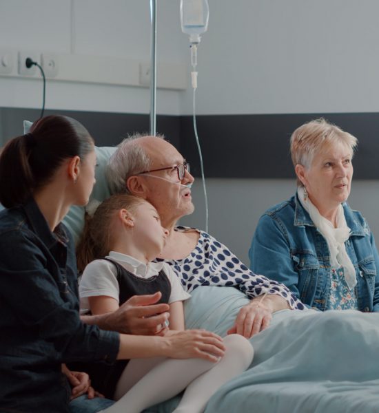 Older man in hospital with family.